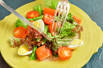 Eating tasty salad with salmon and vegetables at table, closeup