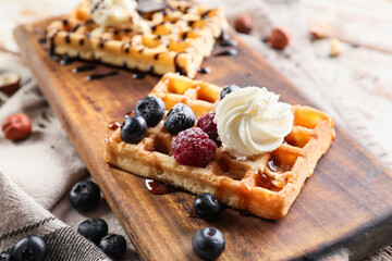 Wooden board of tasty Belgian Waffles with berries on table