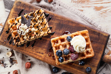 Wooden board of tasty Belgian Waffles with berries on white wooden background