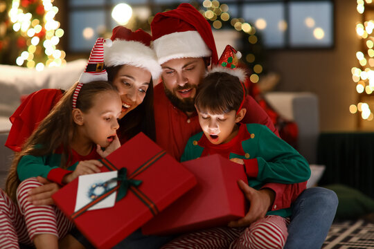 Happy family with kids opening present at home on Christmas eve