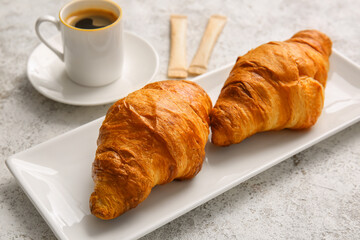Plate with delicious croissants on light background