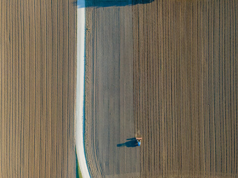 Aerial view of a tractor working in an agricultural field at sunset near Aquileia, Udine, Friuli Venezia Giulia, Italy.