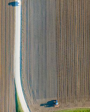 Aerial view of a tractor working in an agricultural field at sunset near Aquileia, Udine, Friuli Venezia Giulia, Italy.