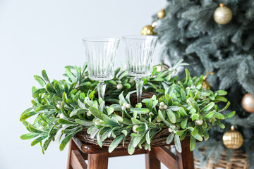 Beautiful mistletoe wreath with glasses on table in room