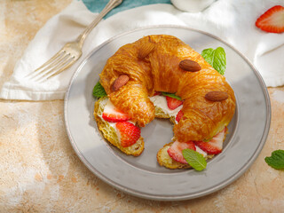French breakfast for one person. Fragrant fresh croissant with strawberries, mint leaves and almond nuts and milk on a white background. There are no people in the photo.