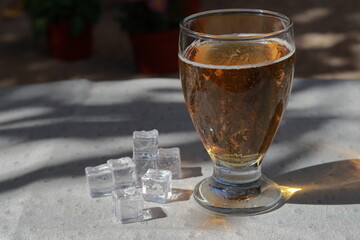 A glass of cold beer with ice cubes