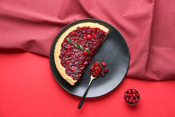 Plate with cut tasty lingonberry pie on color background