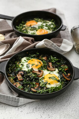 Frying pans with tasty Shakshouka on white background