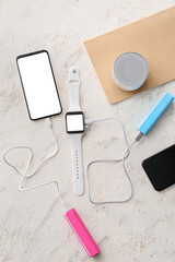 Modern power banks, smartphones, speaker and smartwatch on light background