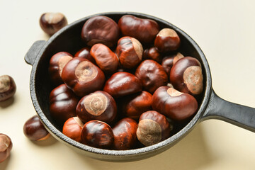 Frying pan with chestnuts on color background, closeup