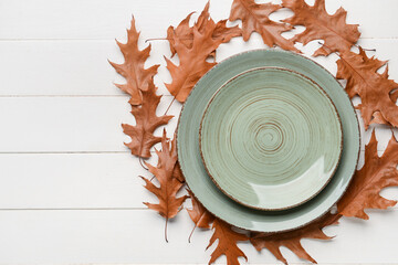 Composition with table setting and autumn leaves on white wooden background