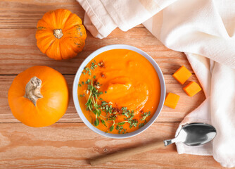 Bowl with tasty pumpkin cream soup on wooden background