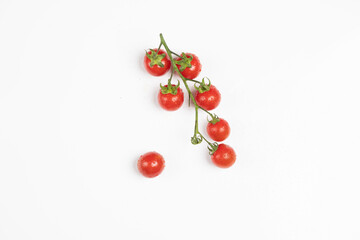 Pomodorini ciliegini freschi attaccati al ramo e sparsi su sfondo bianco / Fresh cherry tomatoes attached to the branch and scattered over white background