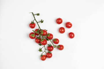 Pomodorini ciliegini freschi attaccati al ramo e sparsi su sfondo bianco / Fresh cherry tomatoes attached to the branch and scattered over white background