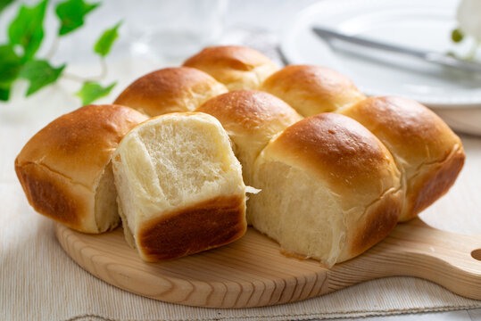 Freshly baked golden brown dinner rolls bread served on wooden board