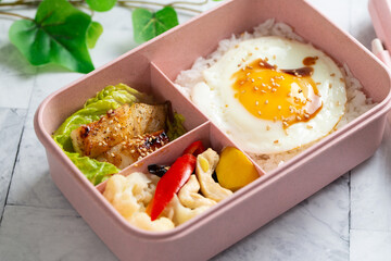 Kid school lunch bento box set of grilled fish, egg, rice and vegetables