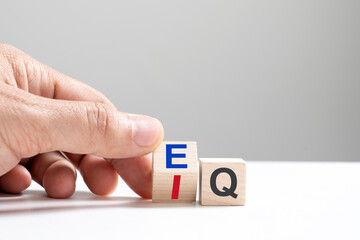 Hand turns a square cube and changes the expression IQ Intelligence Quotient to EQ Emotional...