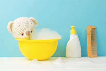 Cute knitted teddy bear taking a bath on a blue background.
