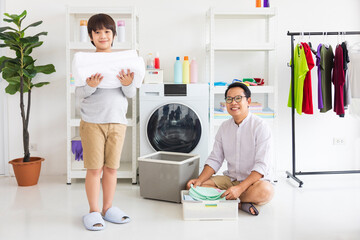 Asian father and son help each other doing laundry together for daily routine chores