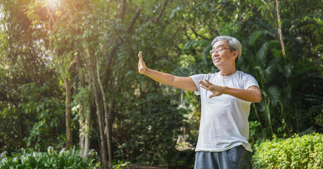 Portrait of healthy happy senior asian old man in the park outdoors exercise stretching his arms....