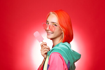Beautiful young woman with bright dyed hair holding ice cream on color background