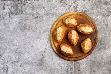 Croissants with cheese and sausage on a round wooden cutting board on a dark grey background. Top view, flat lay