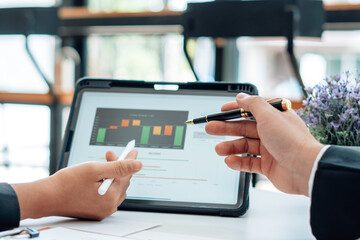 Two businessmen are together analyzing the financial data graph and pointing to the laptop computer screen.