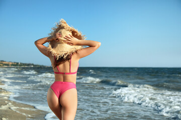 Young woman with attractive body on beach, back view. Space for text