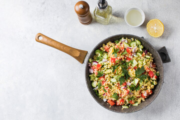 Salad with bulgur, tomatoes, cucumbers and parsley. Tabouleh dish. Oriental cuisine. Copy space.