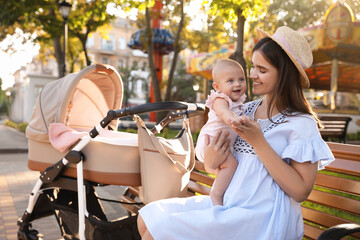 Happy mother with baby sitting on bench in park