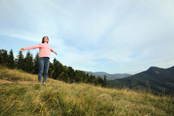 Fototapeta na wymiar Young woman enjoying mountain landscape. Space for text