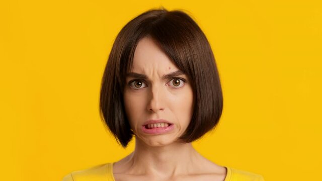 Portrait Of Woman Grimacing Expressing Disgust Wrinkling Nose, Yellow Background