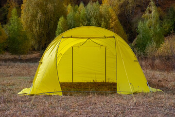 Yellow large basecamp tent on colorful mountains background.