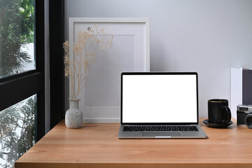 Fototapeta premium Computer laptop, books, coffee cup and picture frame on wooden table.