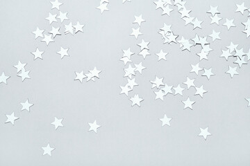 Silver stars confetti on gray background. Christmas or winter festive background