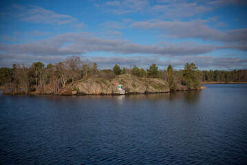 Obraz premium The cliff islet Fläsklösa in the lake Mälaren with a solar powered small lighthouse a sunny and color full autumn day in Stockholm
