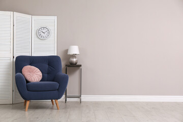 Comfortable armchair and decor near beige wall. Space for text