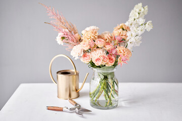 Fototapeta premium Finished flower arrangement in a vase for home. Flowers bunch, set for interior. Fresh cut flowers for decoration home. European floral shop. Delivery fresh cut flower.