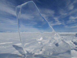 Pure ice of Lake Baikal. A piece of shining ice. Winter when there is a lot of snow.