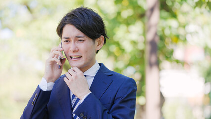 スマホで話す若い男性ビジネスマン