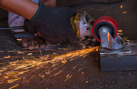 Industrial worker using angle grinder cutting metal. Worker working with angle grinder and has orange sparks. Tool for cut and grinding steel. Safety in industrial workplace. Metal factory industry.