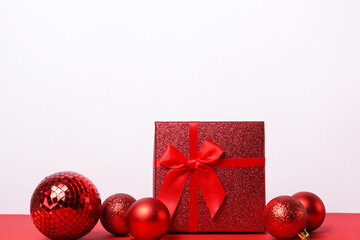 Red gift box with ribbon and balls on white background, greeting card with copy space