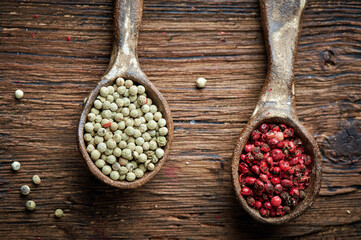 White and red pepper on an ceramic spoon over wooden backround