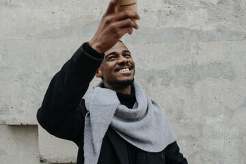 Looking up at a coffee cup cheerful black man in a warm coat