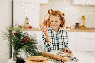 Portrait of a joyful girl holding a Christmas decorative cookie in her hand. Preparation for the holidays, Christmas spirit, Christmas treats