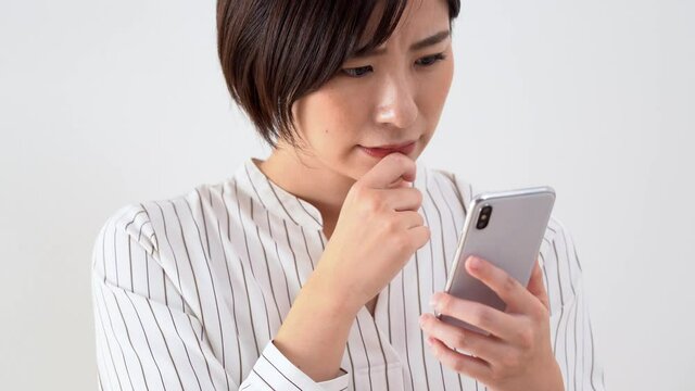 携帯を見ながら悩む日本人女性
