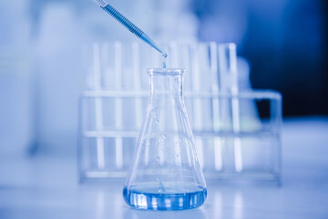 Doctor or scientist using pipette to drop a sample to test tube in medical research lab or science laboratory