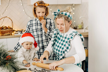 Happy family mother and children son and daughter bake cookies for Christmas. Christmas spirit, a family tradition