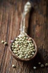 White pepper on an ceramic spoon over wooden backround
