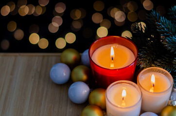Focus and blurred candles put on wooden tray with Christmas tree and ornaments with bokeh light background.
